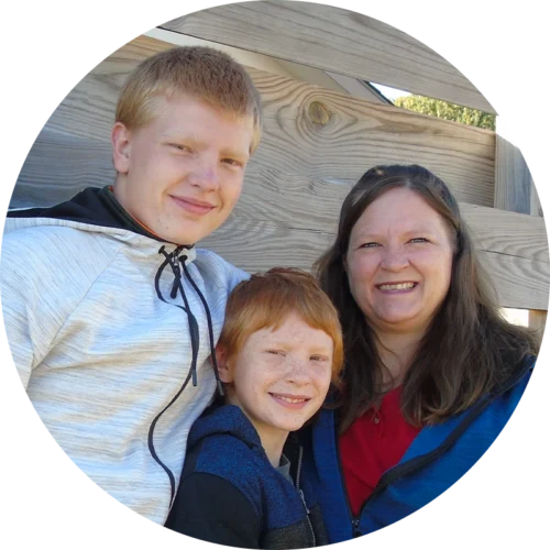 Family partner Cherity and her sons standing in front of a built fence.