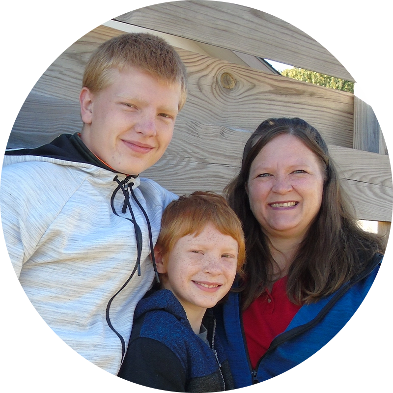 Family partner Cherity and her sons standing in front of a built fence.