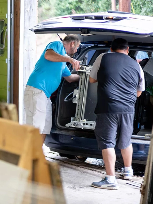 Two people placing donations into the back of an SUV.