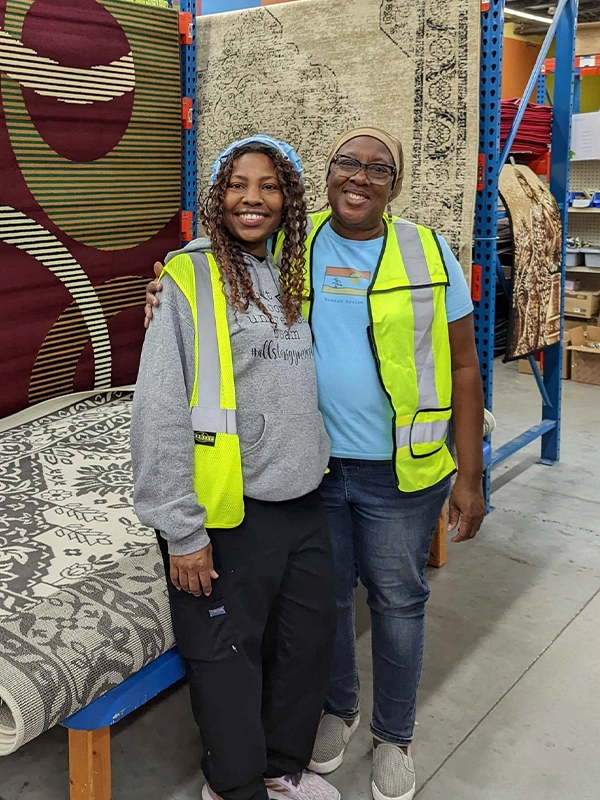 ReStore volunteers standing in front of area rugs.